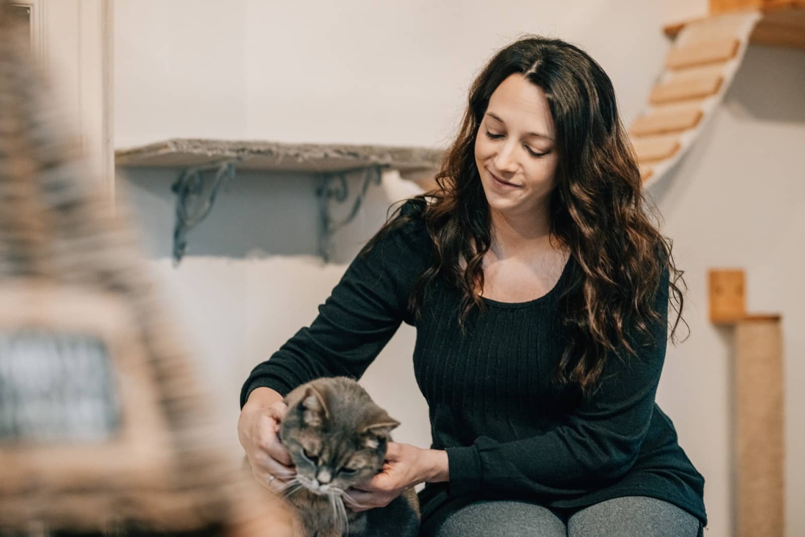 Patricia Metzer sitzt lächelnd im Aufenthaltsraum und streichelt eine graue Katze